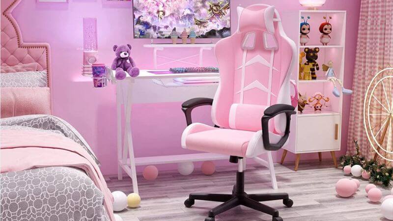 Cadeira gamer rosa e branca em ambiente feminino decorado, ideal para setup de jogos ou home office em espaço moderno com mesa branca e decoração temática.